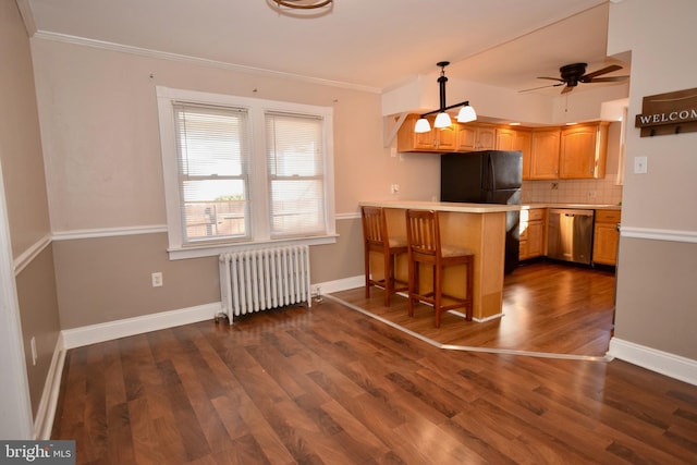 kitchen with kitchen peninsula, stainless steel dishwasher, a breakfast bar, pendant lighting, and radiator heating unit