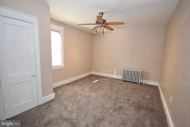 unfurnished room with radiator heating unit, dark carpet, and ceiling fan