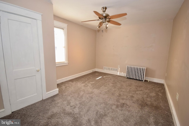 unfurnished room featuring ceiling fan, radiator heating unit, and dark carpet