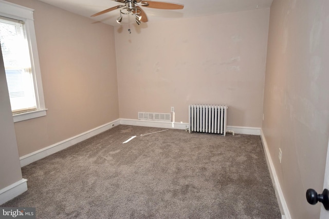 carpeted empty room featuring radiator, a wealth of natural light, and ceiling fan