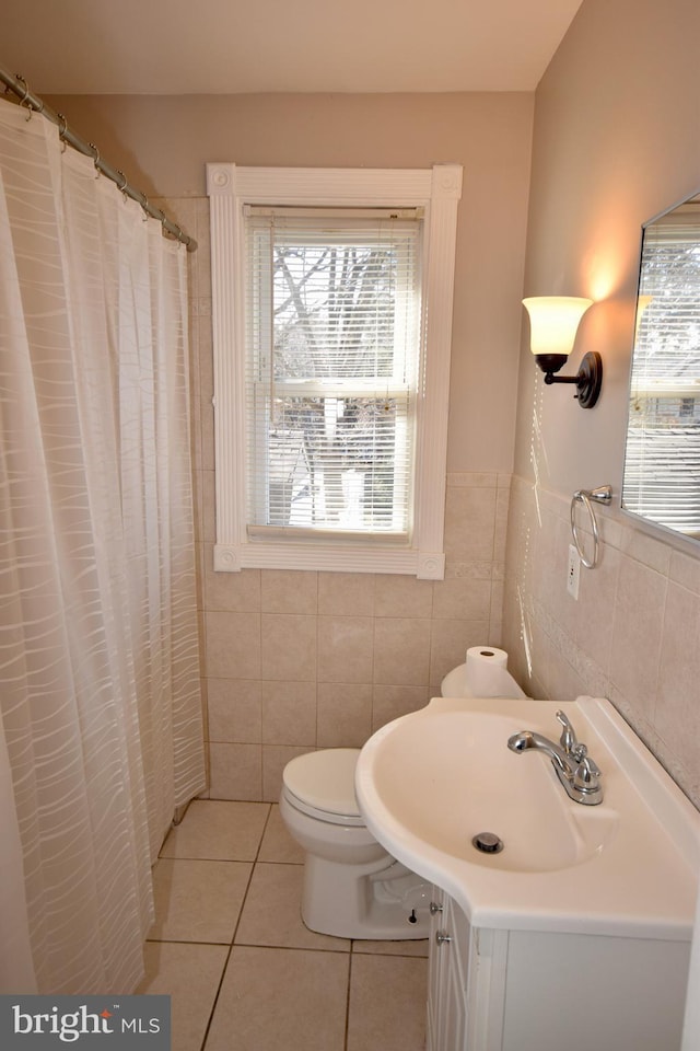 bathroom featuring walk in shower, tile patterned flooring, toilet, vanity, and tile walls