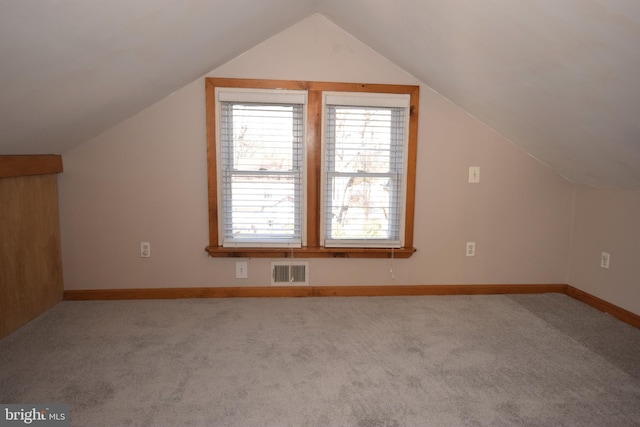 additional living space featuring light colored carpet and vaulted ceiling