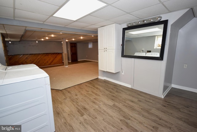 interior space with washing machine and dryer, light hardwood / wood-style floors, a drop ceiling, and wooden walls