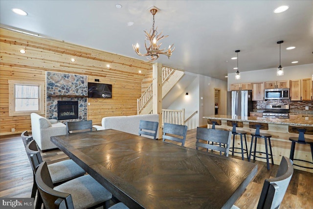 dining room with a fireplace, dark hardwood / wood-style flooring, an inviting chandelier, and wooden walls