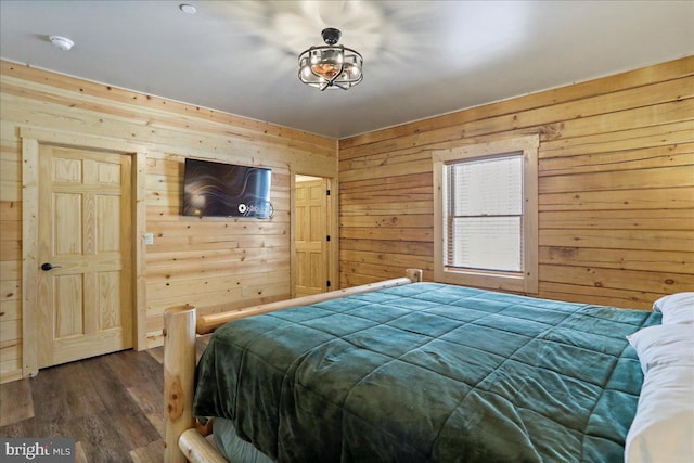 bedroom with dark wood-type flooring and wood walls