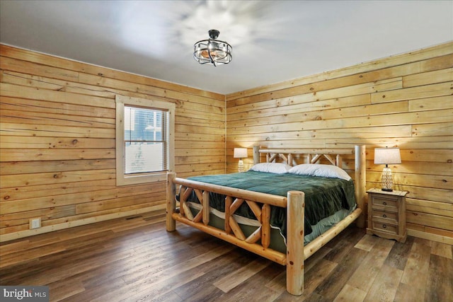 bedroom with dark wood-type flooring and wooden walls