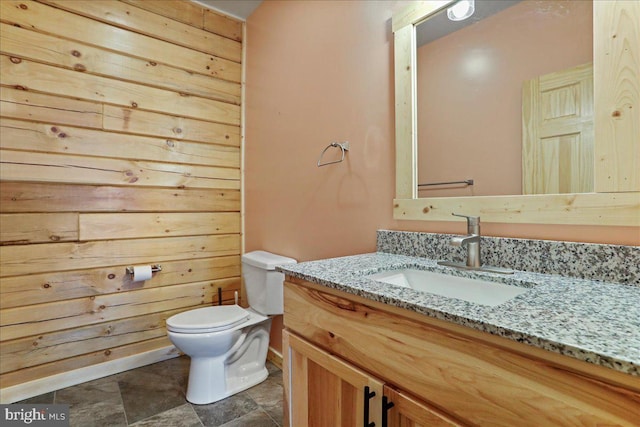 bathroom with toilet, wood walls, and vanity