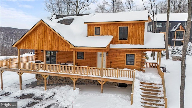 snow covered back of property with a wooden deck