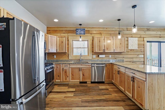 kitchen with appliances with stainless steel finishes, sink, light stone counters, and pendant lighting