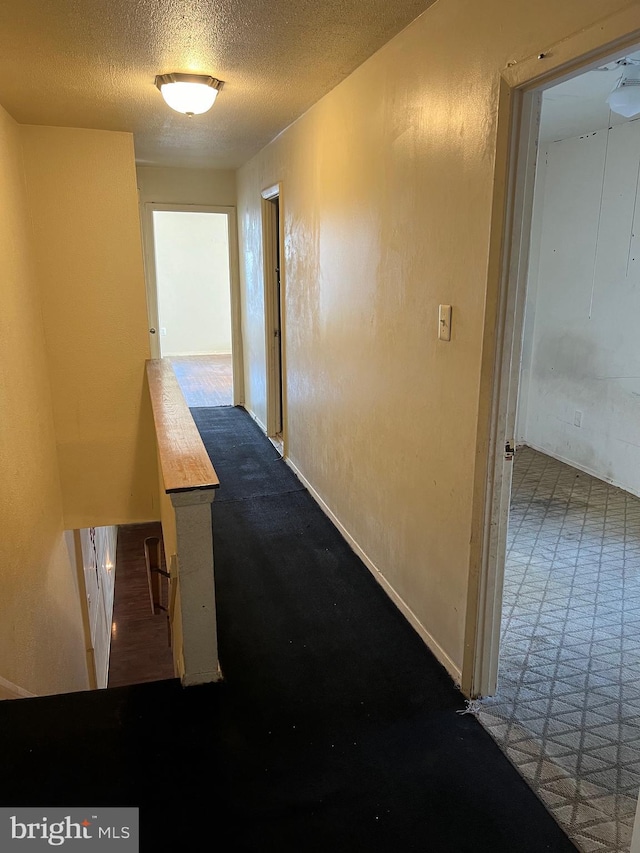 hallway featuring carpet and a textured ceiling