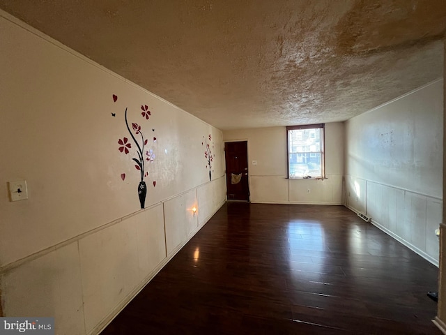 unfurnished room with a textured ceiling and dark hardwood / wood-style floors