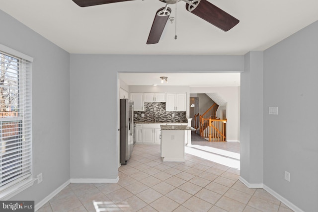 kitchen featuring white cabinets, ceiling fan, light tile patterned floors, backsplash, and stainless steel fridge with ice dispenser