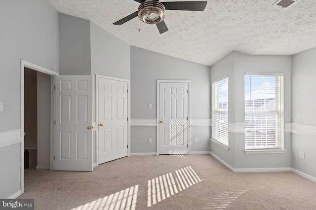 unfurnished bedroom with lofted ceiling, light colored carpet, ceiling fan, and a textured ceiling