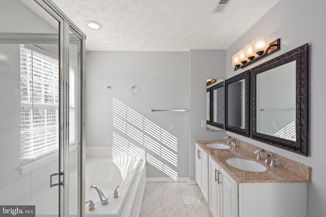 bathroom with vanity, a textured ceiling, and a tub to relax in