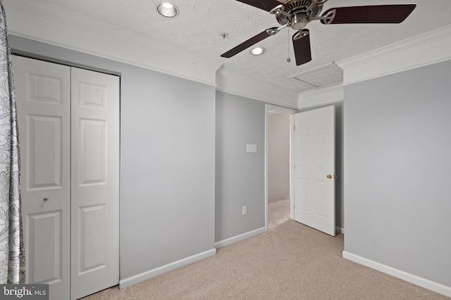 unfurnished bedroom with a textured ceiling, ceiling fan, ornamental molding, a closet, and light colored carpet