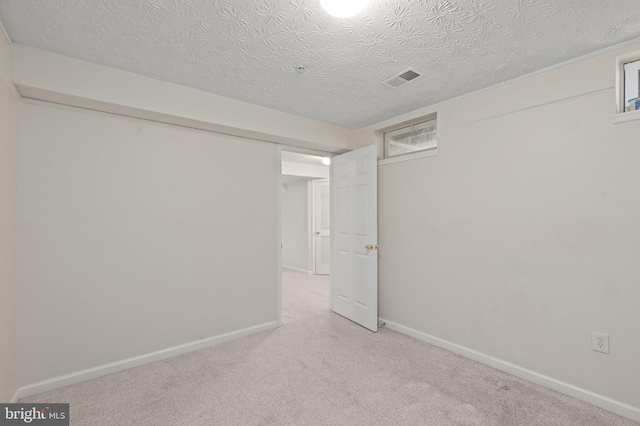 basement featuring a textured ceiling and light colored carpet