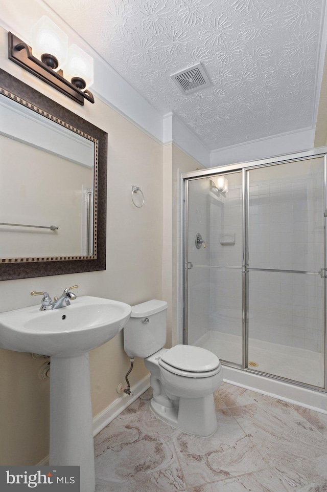 bathroom with a textured ceiling, a shower with shower door, and toilet