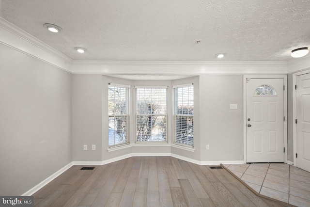 foyer with a textured ceiling, ornamental molding, and wood-type flooring