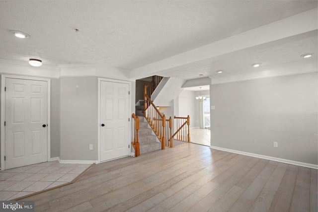 unfurnished room with light hardwood / wood-style floors, an inviting chandelier, and a textured ceiling