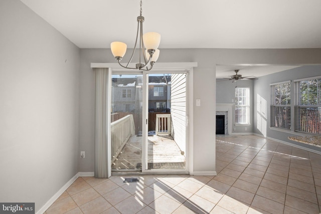 unfurnished dining area featuring light tile patterned flooring and ceiling fan with notable chandelier