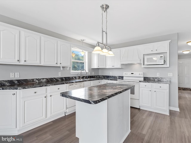 kitchen featuring white cabinets, custom exhaust hood, a kitchen island, and white appliances