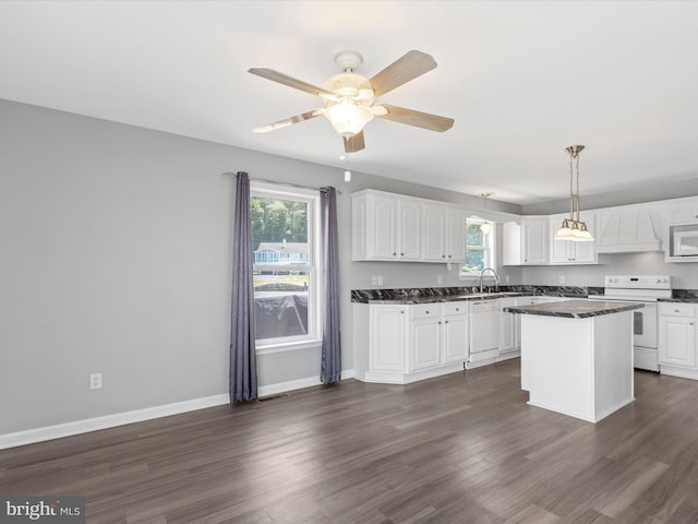 kitchen with a center island, white appliances, sink, hanging light fixtures, and white cabinetry