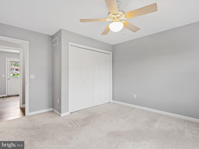 unfurnished bedroom featuring ceiling fan, light colored carpet, and a closet