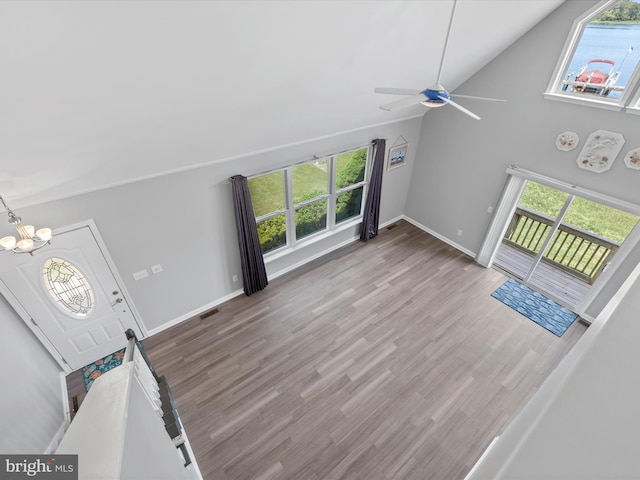 unfurnished living room featuring hardwood / wood-style floors, ceiling fan with notable chandelier, a healthy amount of sunlight, and high vaulted ceiling