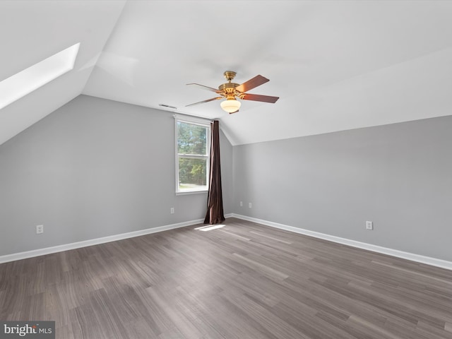 additional living space with ceiling fan, vaulted ceiling with skylight, and wood-type flooring