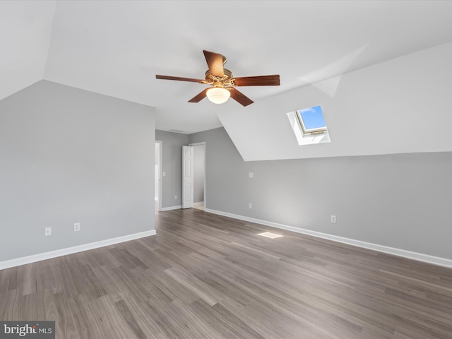 additional living space featuring hardwood / wood-style flooring, lofted ceiling with skylight, and ceiling fan