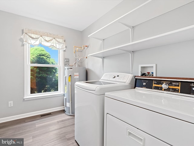 washroom featuring independent washer and dryer, electric water heater, and light hardwood / wood-style flooring