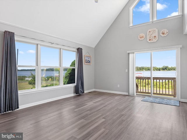 unfurnished living room featuring a water view, wood-type flooring, and high vaulted ceiling