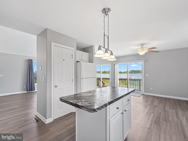 kitchen with white cabinetry, ceiling fan, dark hardwood / wood-style flooring, white fridge, and a kitchen island