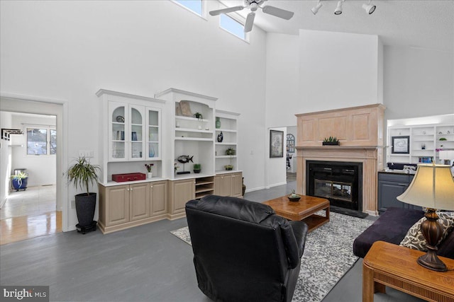 living room featuring ceiling fan, a towering ceiling, a wealth of natural light, and wood-type flooring