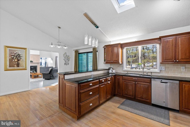 kitchen with decorative light fixtures, tasteful backsplash, sink, stainless steel dishwasher, and kitchen peninsula