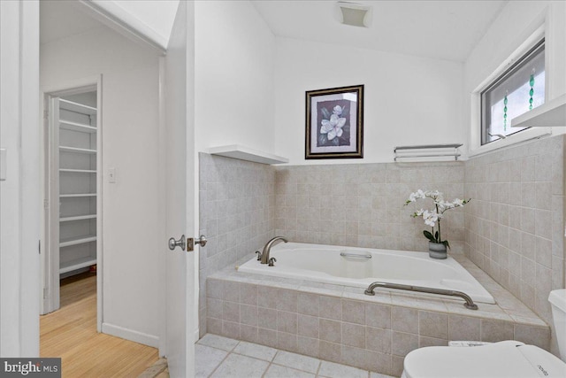 bathroom with tile patterned floors, toilet, and tiled tub