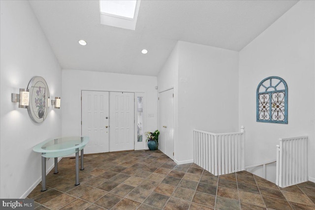 foyer entrance featuring vaulted ceiling with skylight