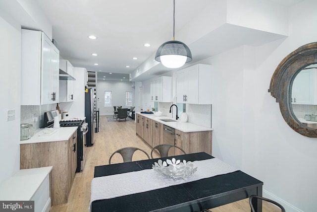 kitchen featuring white cabinets, a sink, stainless steel appliances, light countertops, and backsplash