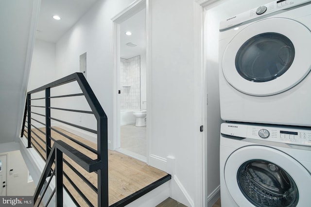 clothes washing area featuring stacked washer / drying machine, laundry area, baseboards, and recessed lighting