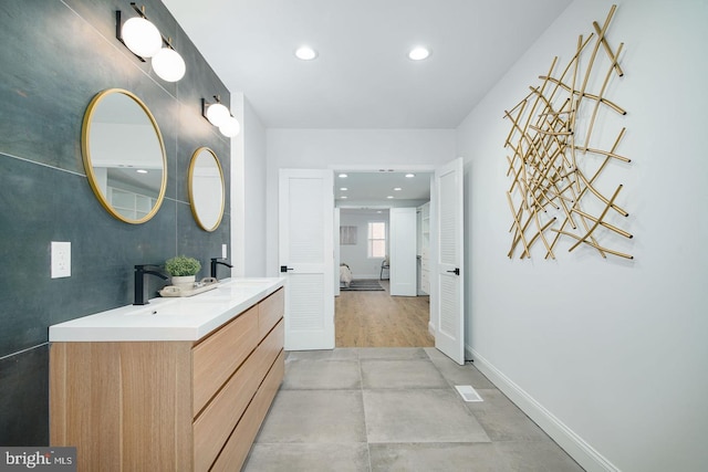 full bath with double vanity, baseboards, a sink, and recessed lighting