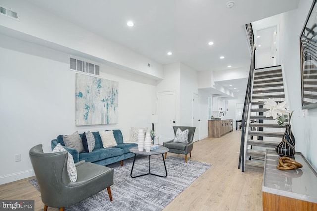 living area featuring light wood finished floors, stairway, and visible vents