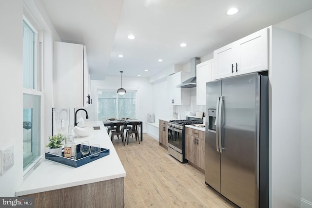 kitchen with wall chimney range hood, stainless steel appliances, light wood-style floors, and recessed lighting