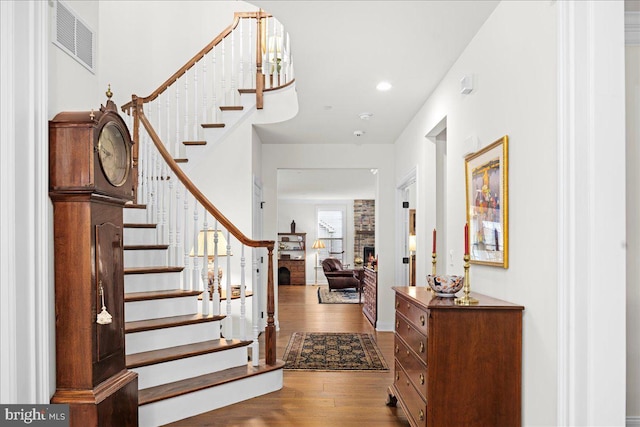 foyer entrance with hardwood / wood-style floors and a brick fireplace