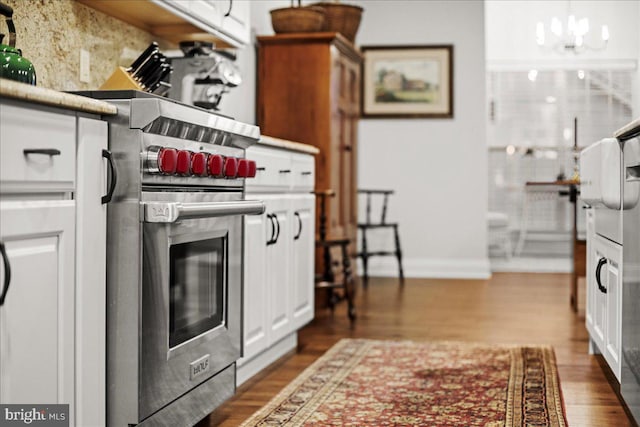 kitchen with white cabinetry, premium range, dark hardwood / wood-style flooring, and a notable chandelier