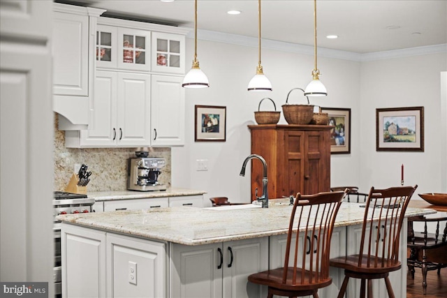 kitchen with pendant lighting, white cabinetry, sink, a center island with sink, and stainless steel gas range