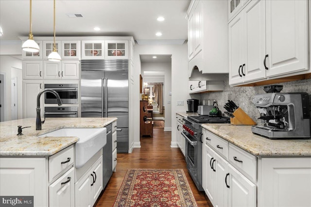 kitchen featuring white cabinetry, premium appliances, decorative light fixtures, and light stone countertops