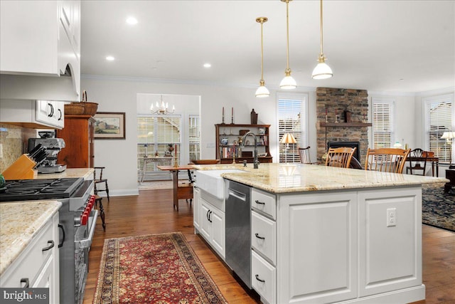 kitchen featuring pendant lighting, white cabinetry, a kitchen island with sink, stainless steel appliances, and light stone countertops