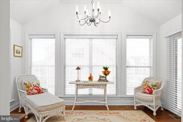 living area featuring vaulted ceiling, plenty of natural light, wood-type flooring, and a notable chandelier