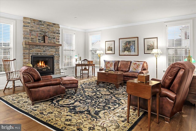 living room with a stone fireplace, dark wood-type flooring, and ornamental molding