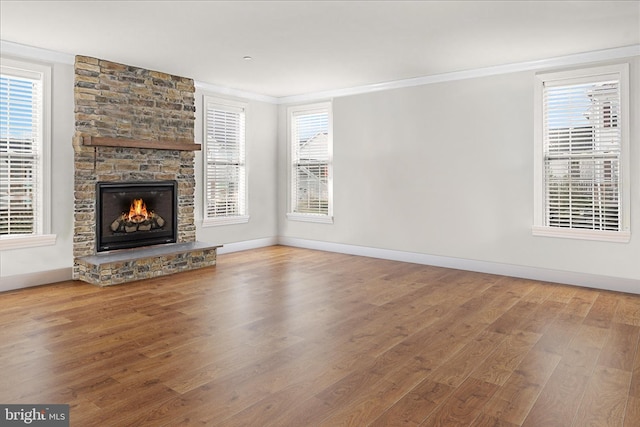 unfurnished living room featuring a stone fireplace, wood-type flooring, and ornamental molding